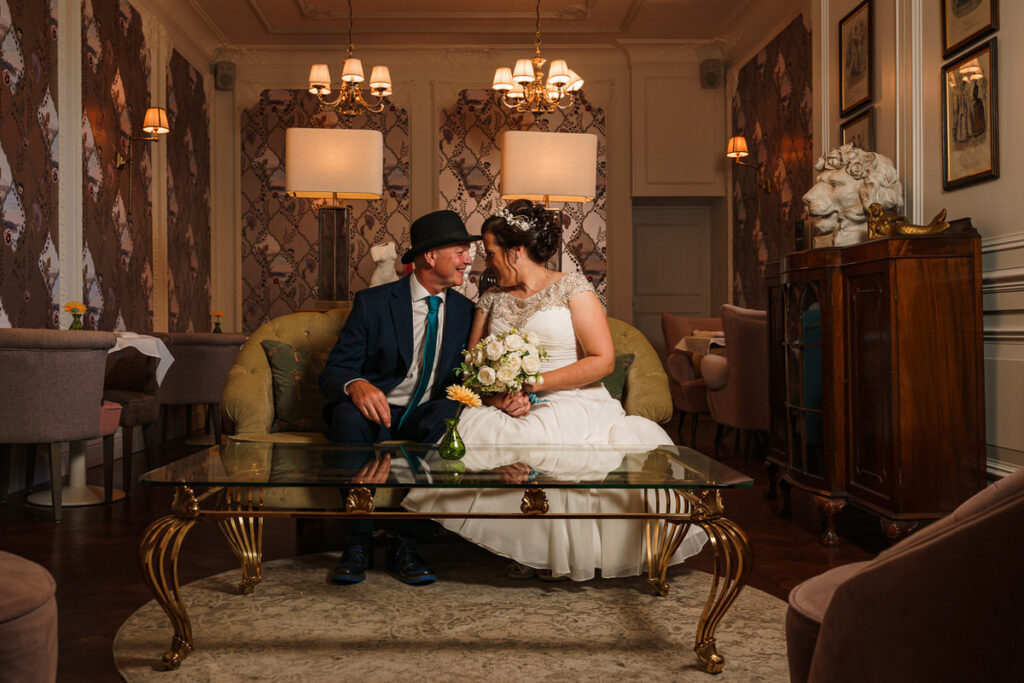 Married couple sat on sofa in ornate lounge at The Bedford Swan Hotel